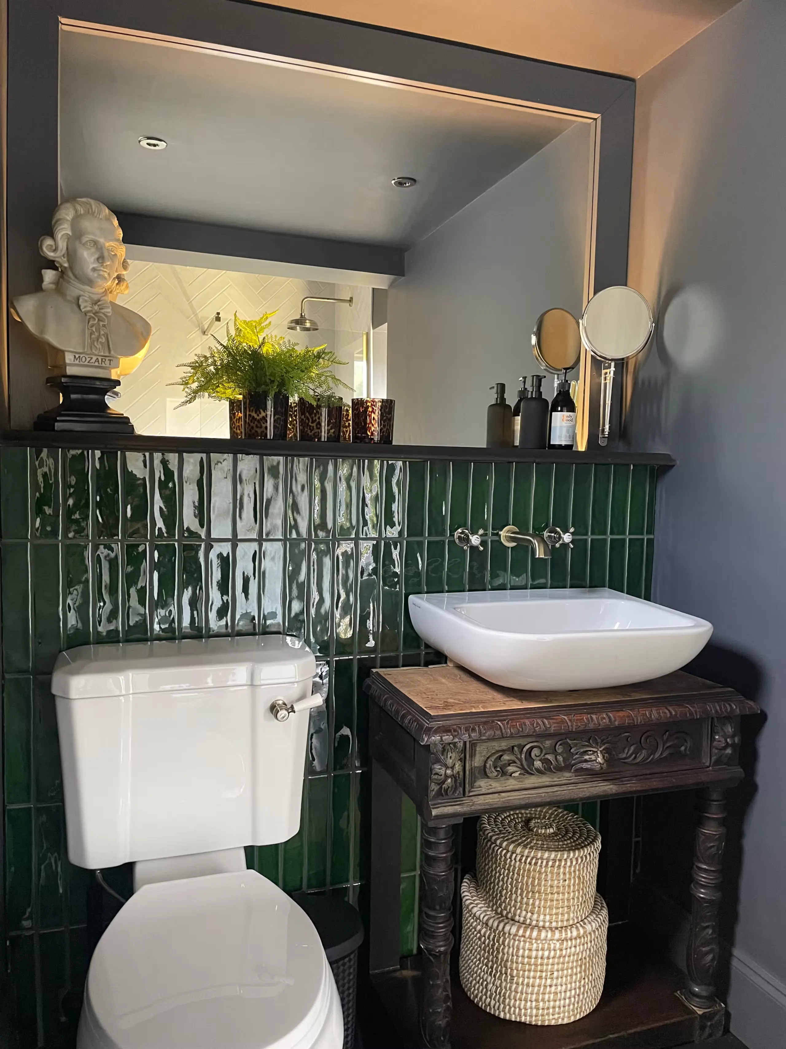 Finished bathroom with green tiles and an antique washstand basin