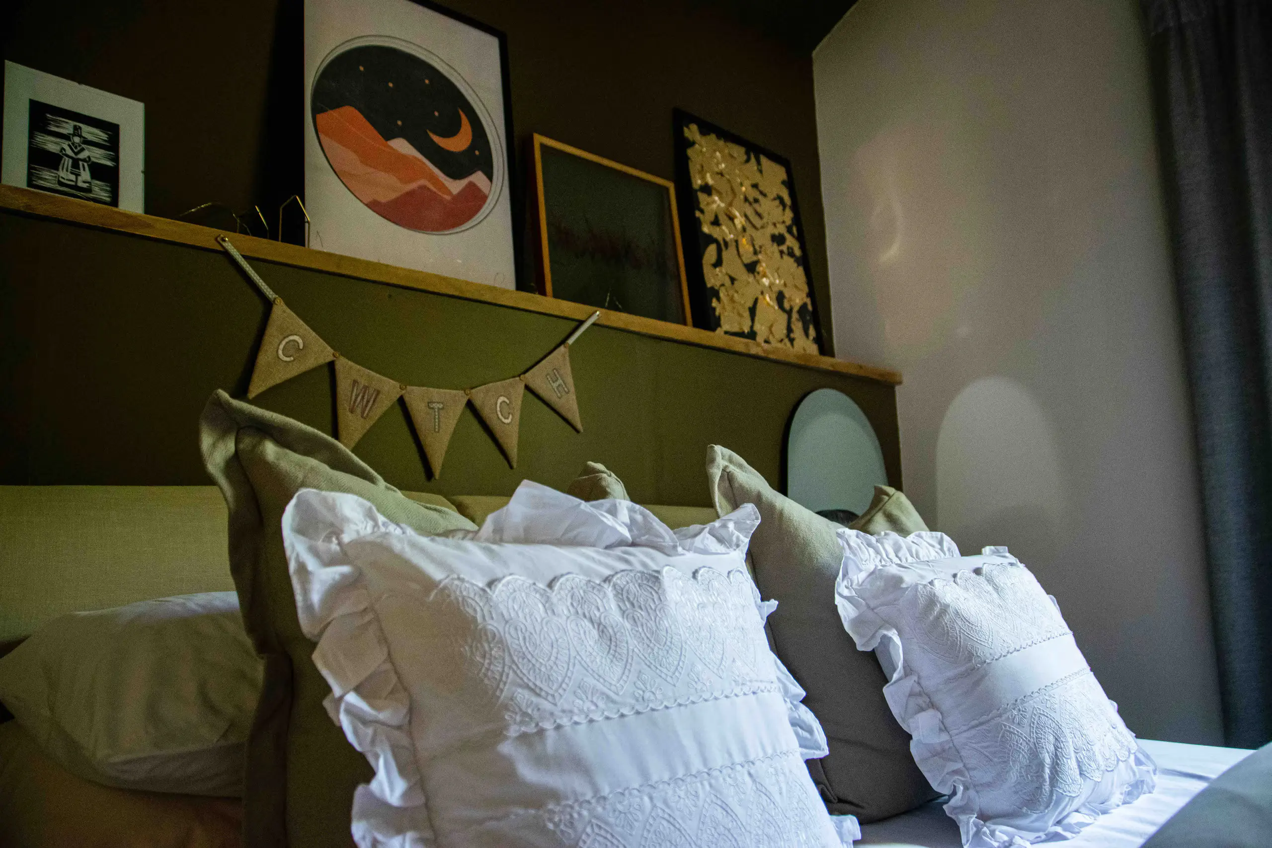 Bedroom detail: art shelf, olive-green walls and hessian CWTCH bunting