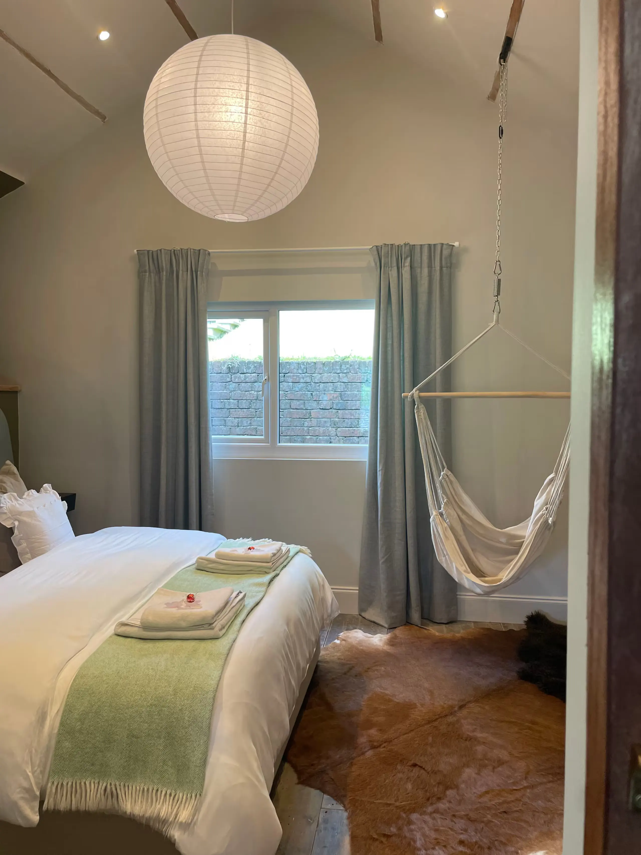 Bedroom at The Old Exchange with a king-size bed, paper lantern and hanging hammock swing chair