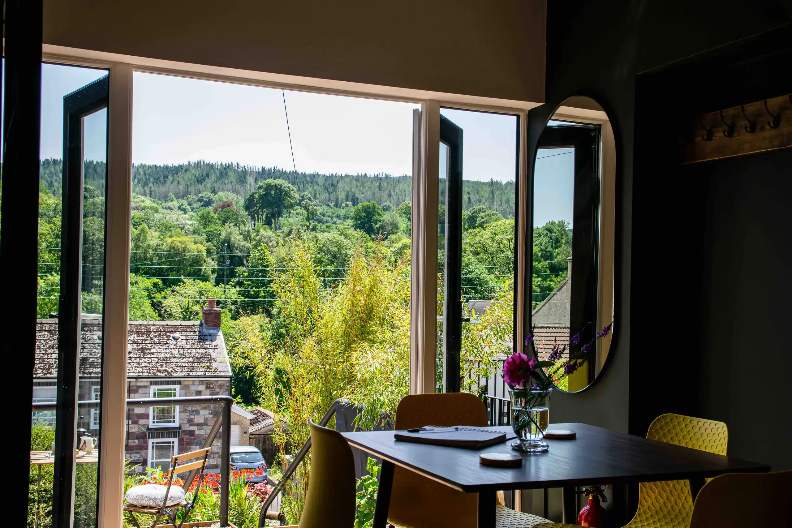 Dining nook with open windows framing the wooded hillside above Abercraf