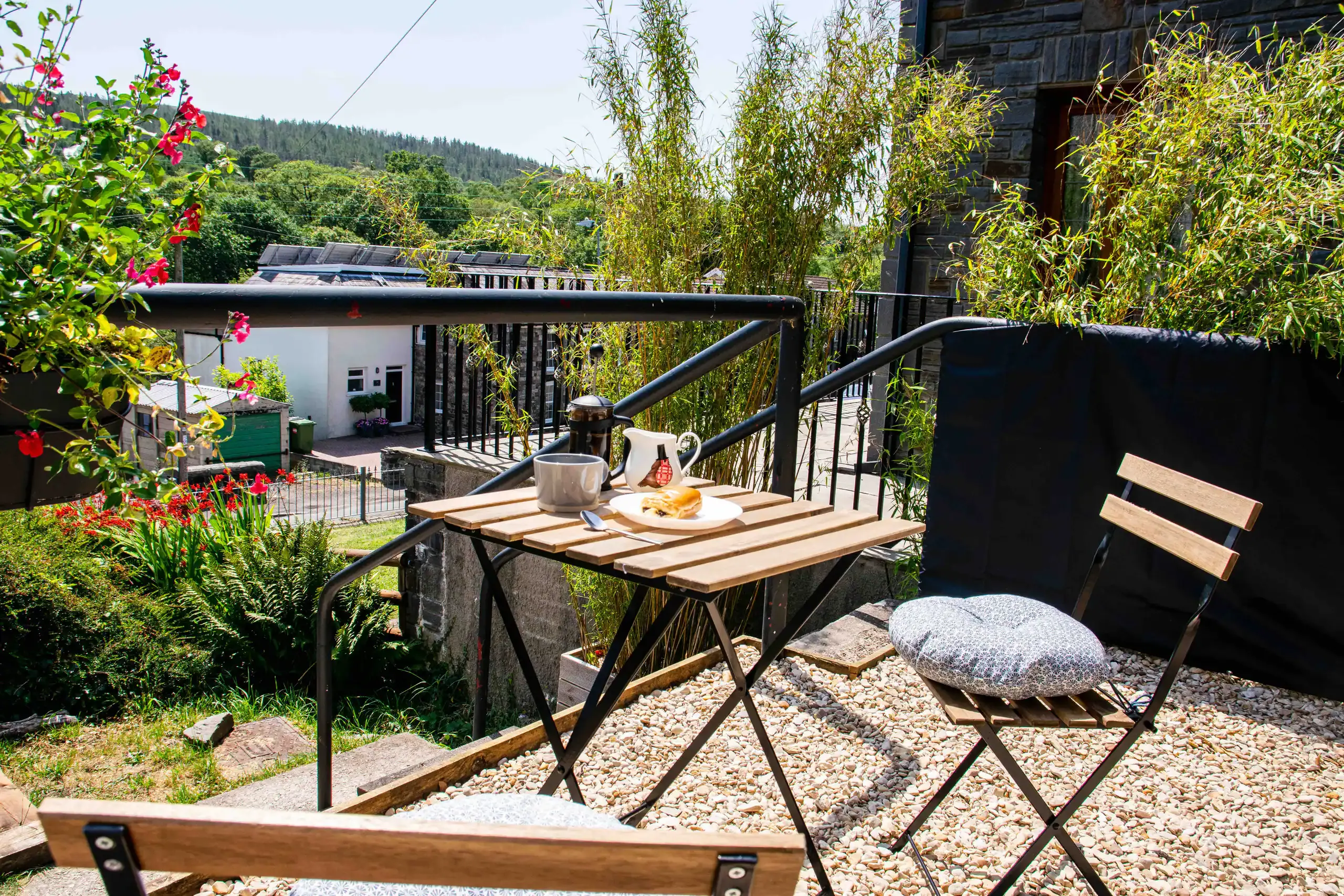 Gravelled front patio with a bistro table and chairs overlooking the hillside