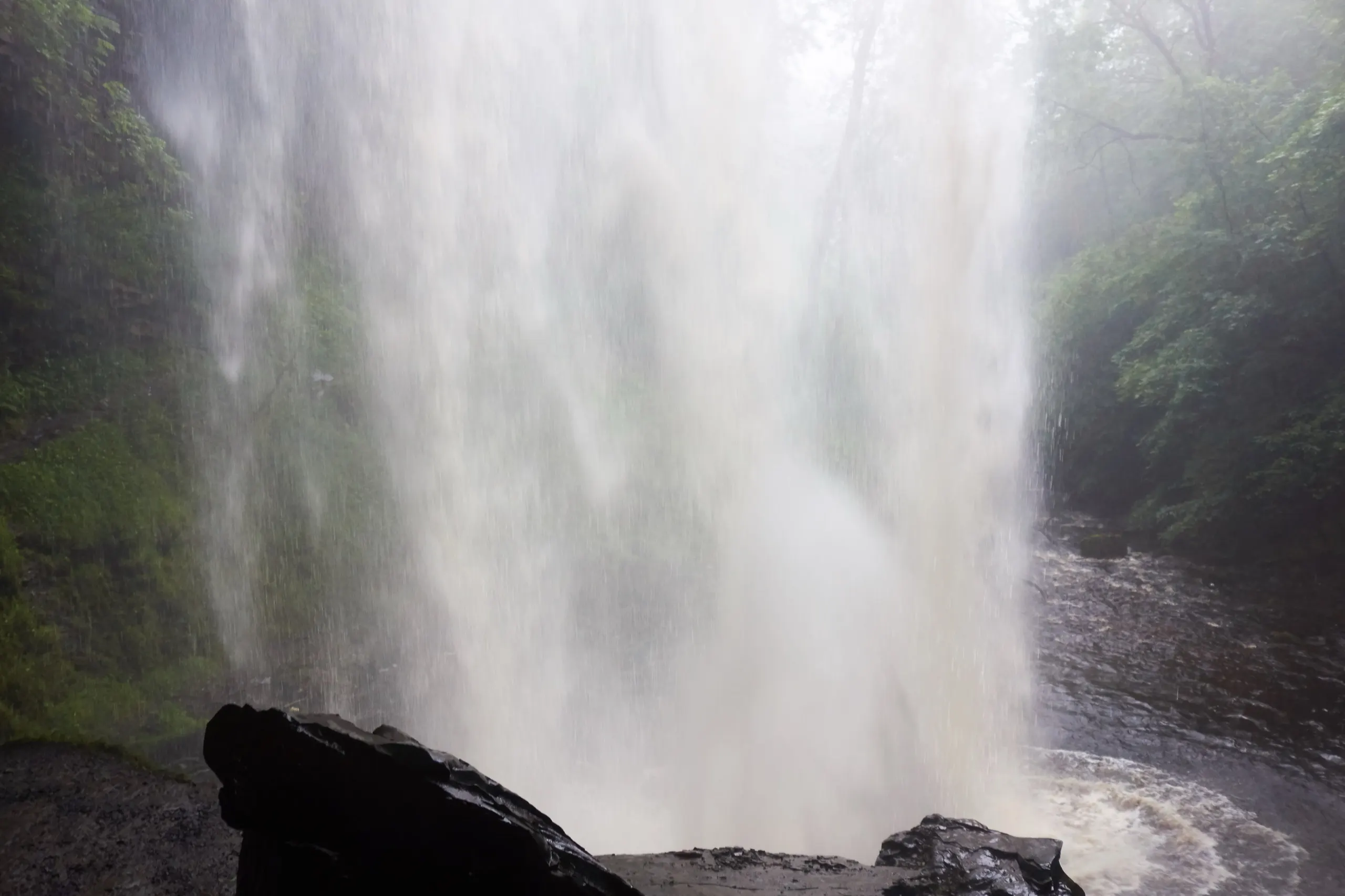 Looking out from behind the falling curtain of Henrhyd Falls