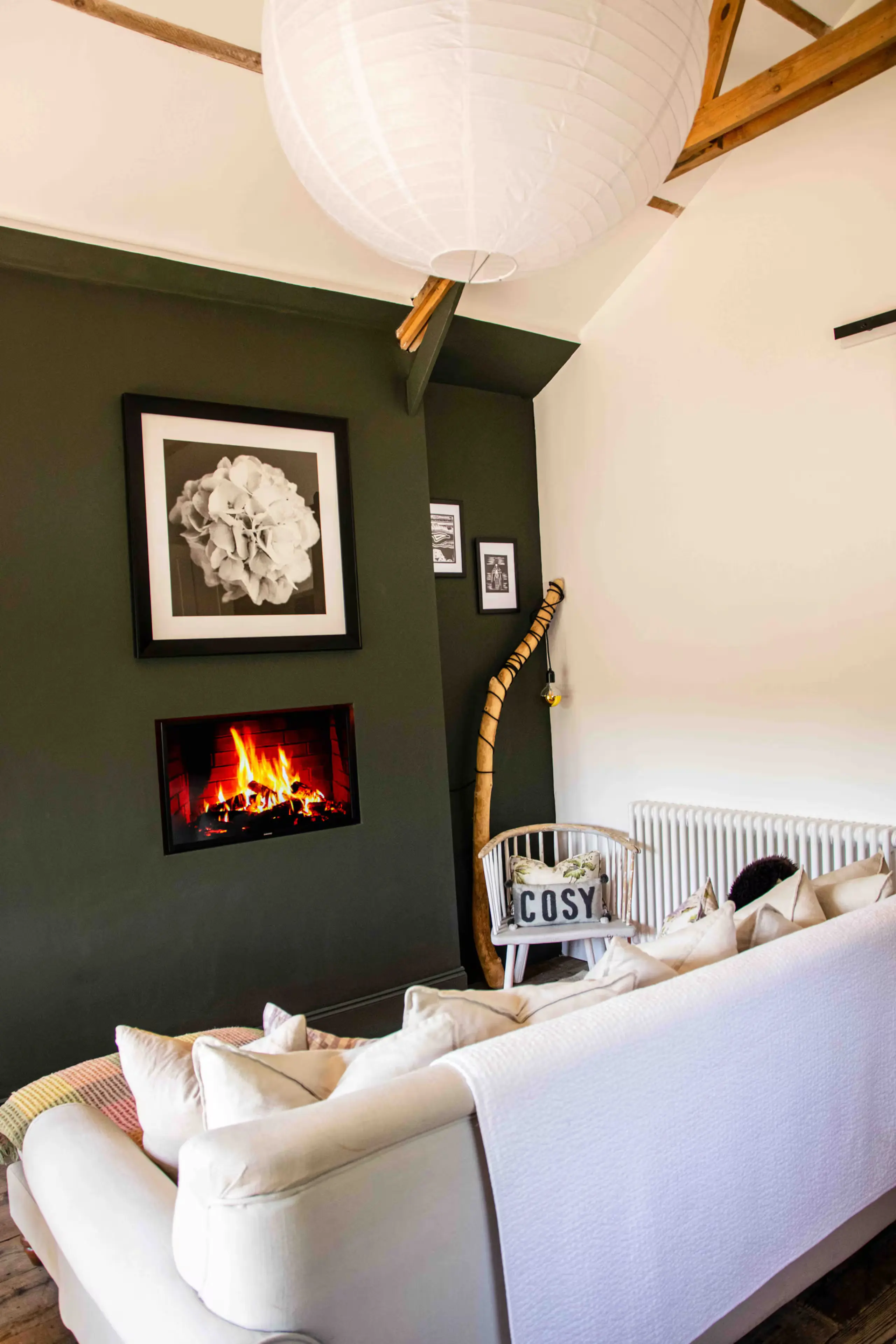 Living room with deep green feature wall, inset fire and a white corner sofa