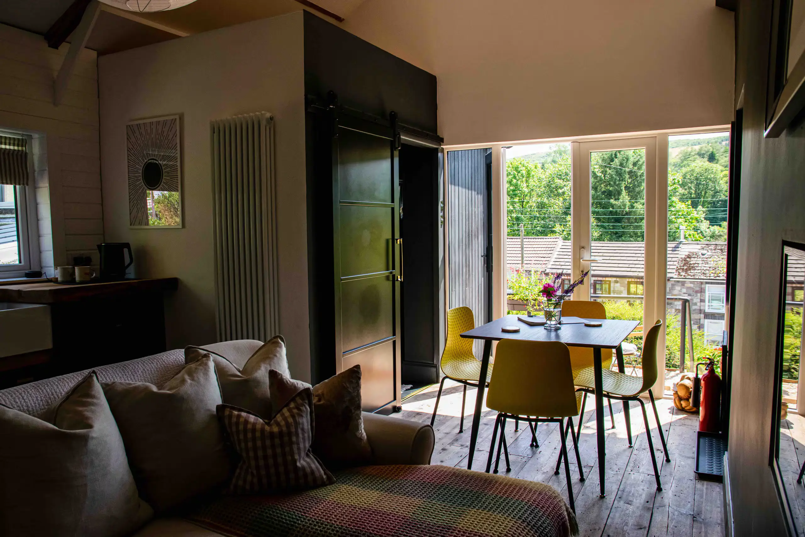 Living space with corner sofa and dining table by the open French doors