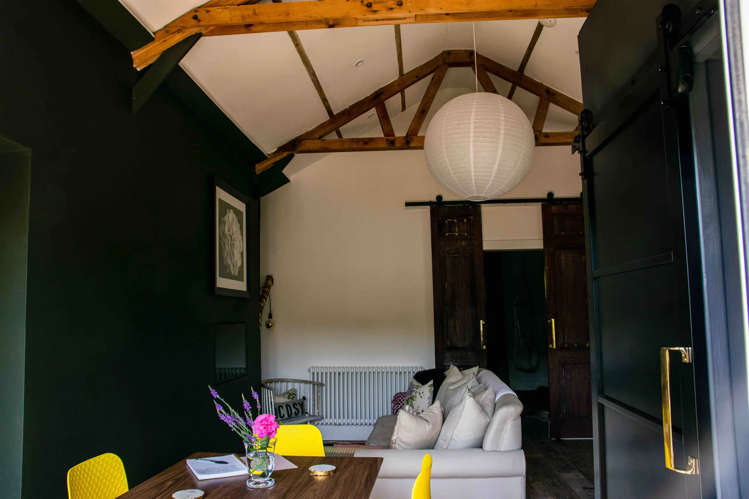 Vaulted living room with original timber beams, paper lantern and reclaimed barn doors