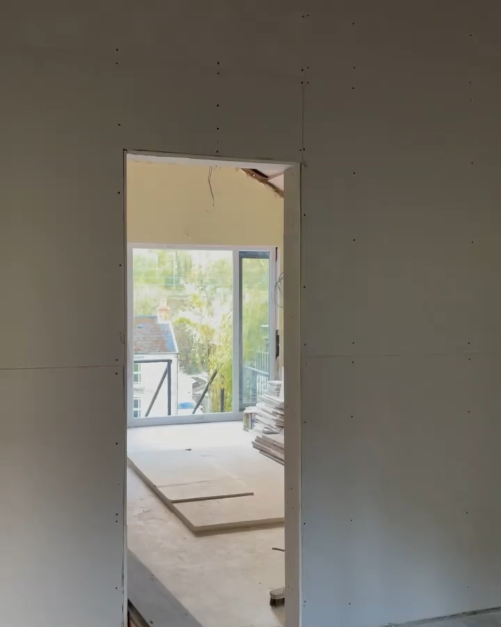 Mid-renovation: bare plasterboard walls and a doorway looking through to the window opening